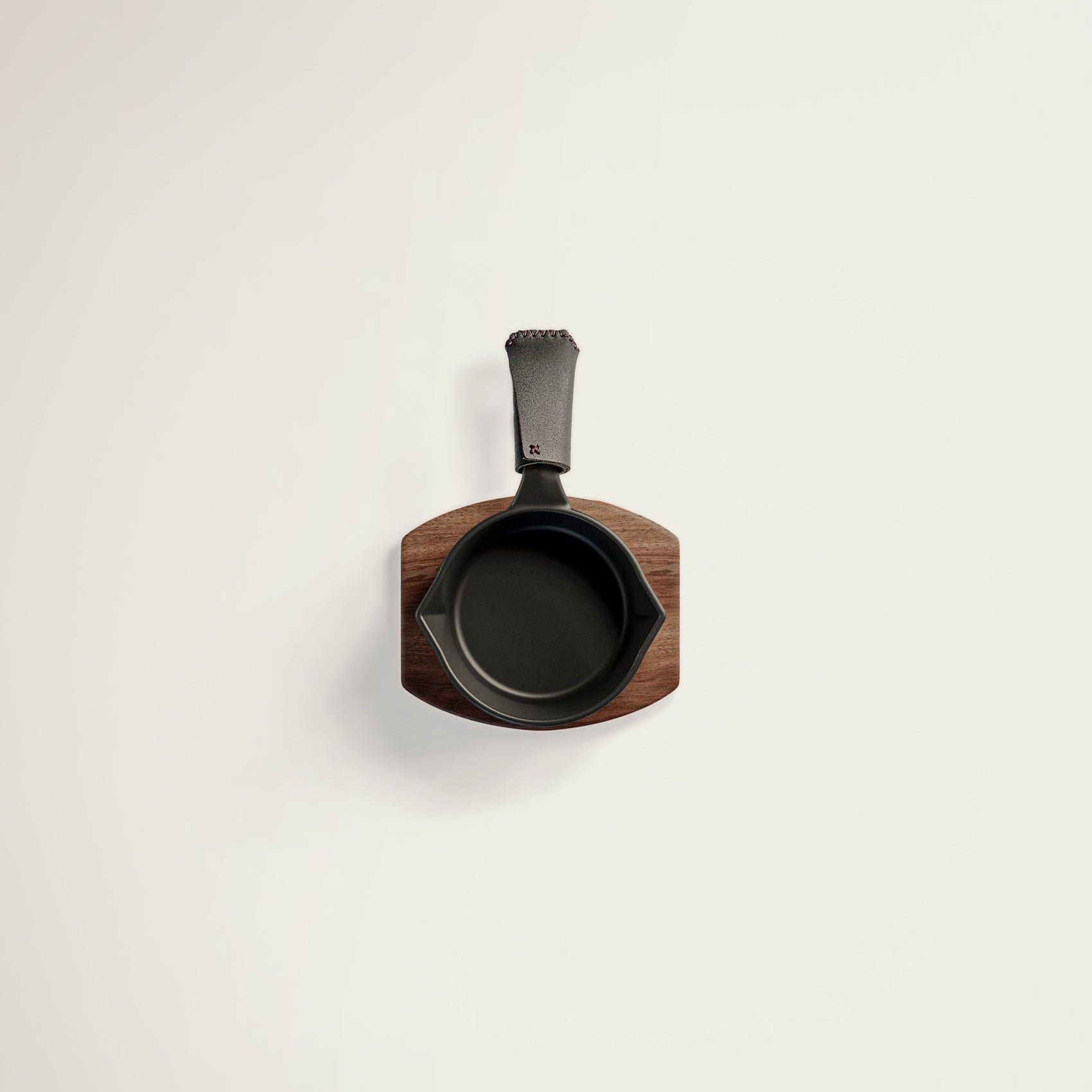 Small black cast iron skillet with wooden handle on a light gray background
